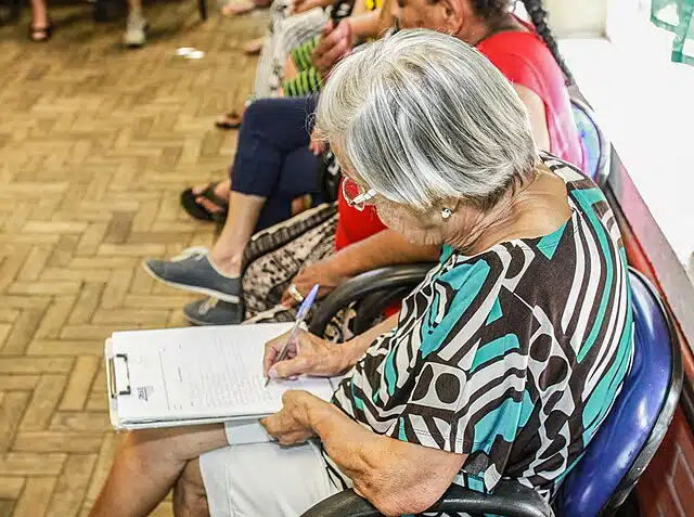 – Idosa preenche papelada. Créditos: Wikipedia

